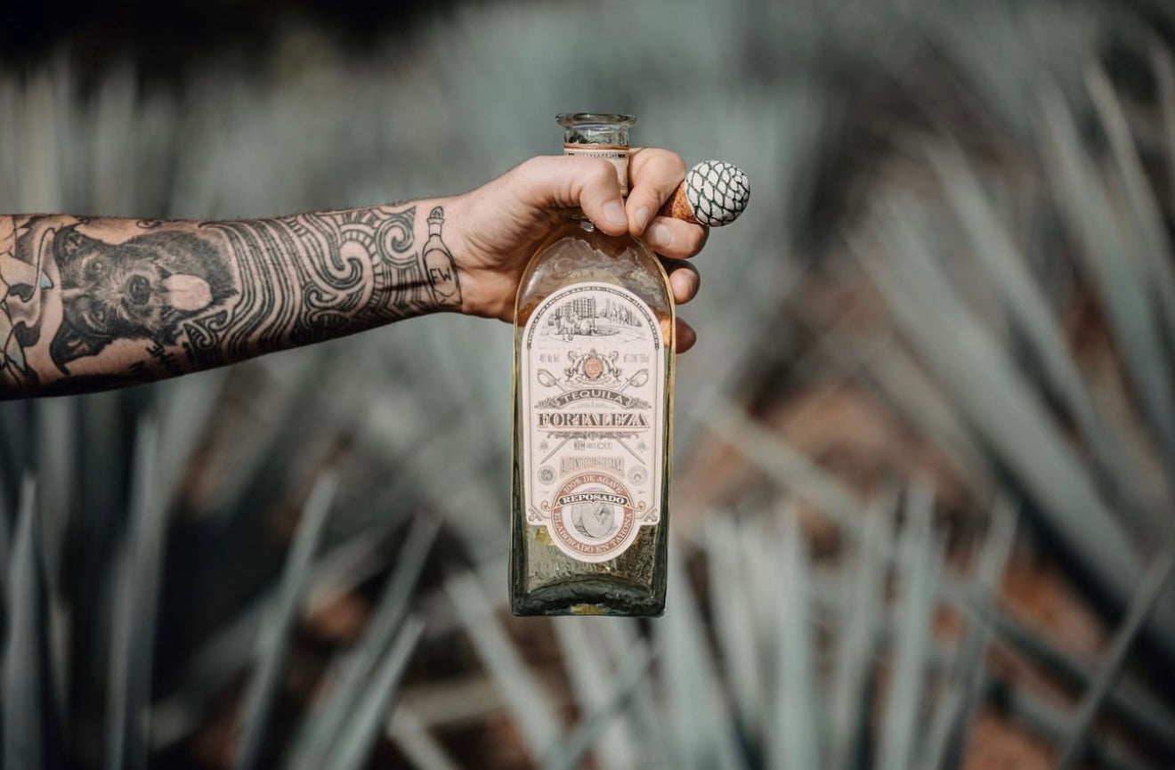 Person holding a bottle of Folleto Fortaleza with a blurred natural background